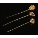 Three 15ct gold stick pins. Two set with single ruby stones, the other set with a diamond.