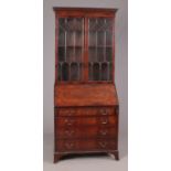 A late Georgian style figured mahogany astragal glazed bureau bookcase with shaped and fitted