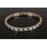 An Art Deco diamond and emerald set bangle. 10.35g.