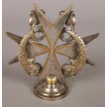 A silver plated car mascot. In the form of a Maltese cross surmounted by a pair of dolphins. Stamped