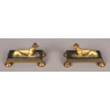 A small pair of bronze mantel figures formed as recumbent greyhounds. Each raised on a bevelled