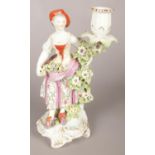 An 18th century Derby porcelain figural candlestick modelled as a lady collecting flowers. 25cm.