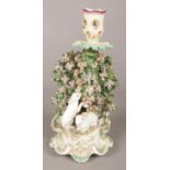 An 18th century Derby porcelain candlestick, with white rabbits, bocage and floral thumbpiece to