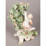 An 18th century Derby porcelain figure, modelled as a putti with bocage. 20cm. Missing right hand