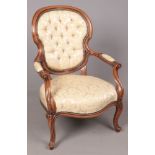 A carved mahogany spoon back arm chair with cream buttoned upholstery.