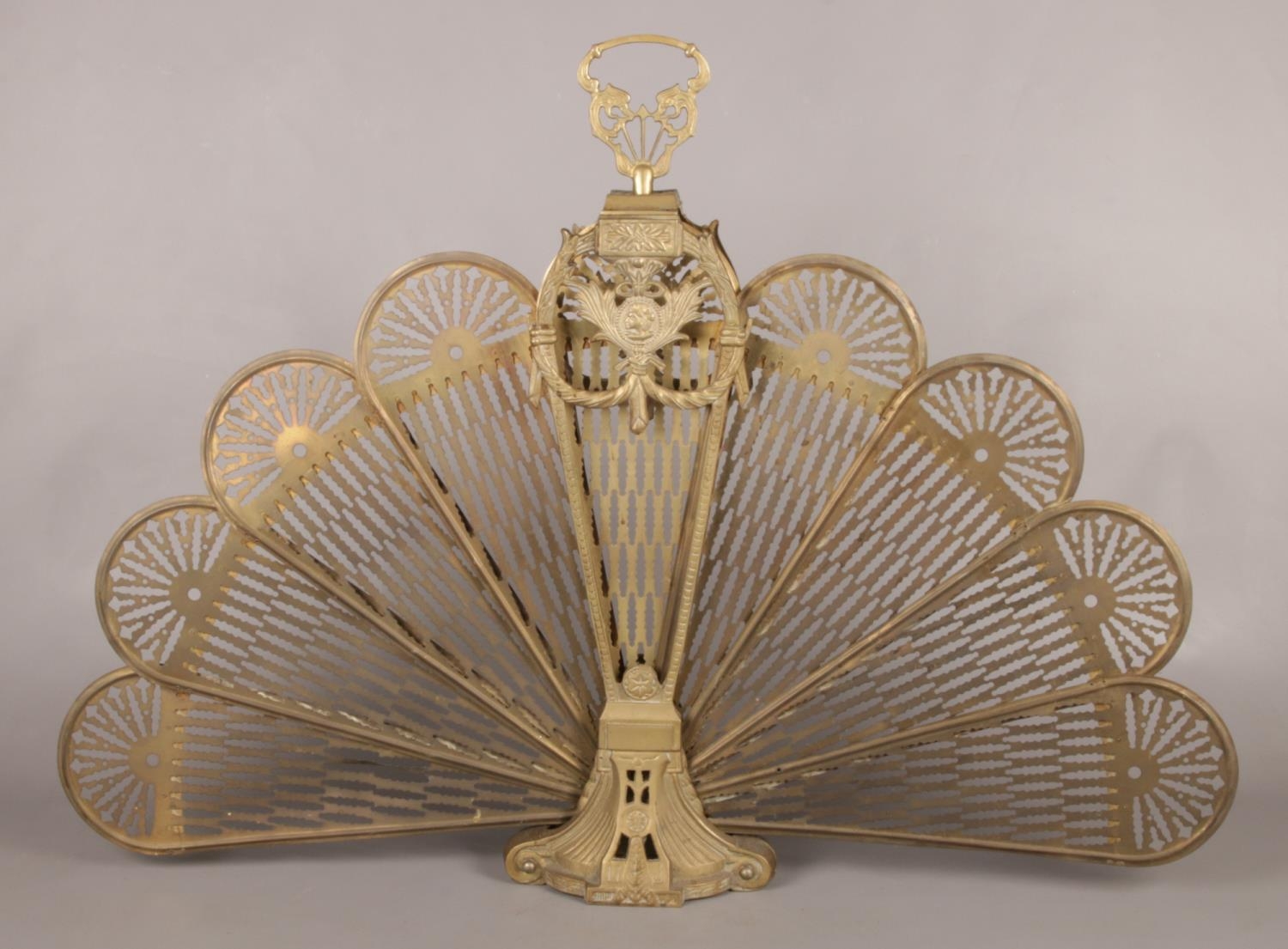 An ornate brass and mesh folding fan shaped fire guard.