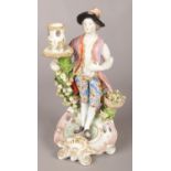 An 18th century Derby porcelain figural candlestick modelled as a gentleman with flower basket.