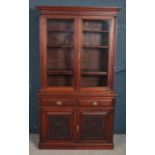 A early 20th century carved mahogany bookcase with fitted cutlery drawers with contents.