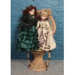 A small wicker chair with two Victorian dressed bisque dolls.