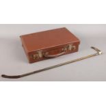 A vintage Swaine & Adeney riding crop along with a small vintage suitcase. The crop with horn handle