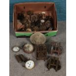 A box of clock parts for spares/repairs. Including movements, faces, coils, etc.