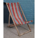 A vintage folding deckchair with striped seat cover.