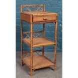 A bamboo three tier side table with top hinged drawer. Height: 71cm.