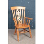 A beech Windsor armchair with stretcher supports.