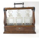 A LATE VICTORIAN TANTALUS with cut glass decanters with stoppers in place and EPNS stamped metal