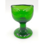 A vintage green glass eyewash bath standing approx 7cm tall.