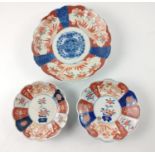 A TRIO of 19th century hand-painted IMARI plates, the largest 21cm diameter, the 2 smaller plates