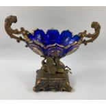 A VICTORIAN TABLE FRUIT BOWL in blue glass with gilt design and twin handles of lions sitting on a