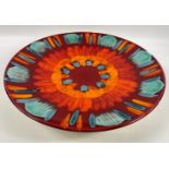 A vibrant large POOLE POTTERY charger in shades of volcanic orange, scarlet and teal, 41cm