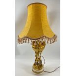 An ornate table lamp with marble base, gilt supports leading to rams' heads anda raw silk shade,