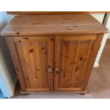 A two door pine cabinet with two doors and a storage shelf on bun feet - with a pull out shelf -