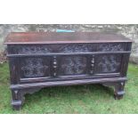 An antique oak blanket box, with roundel carved front and plain rising lid, raised on bracket feet