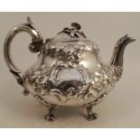 A Victorian silver teapot, with floral finial and embossed decoration, raised on four scroll feet,