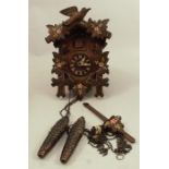 A 20th century Black Forest carved cuckoo clock, carved with leaves and a bird and painted with
