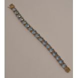 A blue topaz set 9 carat gold bracelet, the seventeen oval cuts to a pierced box clasp, 20cm long,