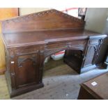 A late 19th century oak sideboard, with carved triangular back, fitted with a central drawer flanked