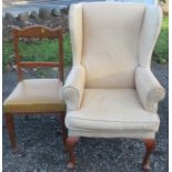 An upholstered wing armchair, together with an oak dining chair