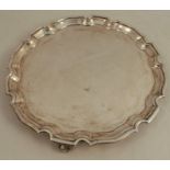 A silver salver, with shaped edge, raised on three scroll feet, Sheffield 1922, weight 18oz