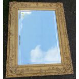 A rectangular gilt framed wall mirror, with decorative mirror plate and scrolls to the frame,