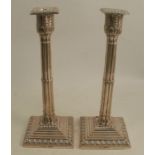 A pair of silver candlesticks, with leaf moulded capitals, cluster columns to stepped square