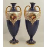 A pair of Royal Worcester twin handled pedestal vases, decorated with a circular panel of fruit to a
