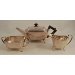 A silver three piece tea set, of rectangular form with canted corners, raised on scroll legs,