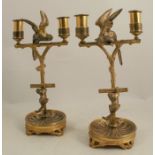 A pair of 19th century ormulu candlesticks, the two light sticks modelled as a parrot on a stand