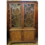 A Georgian style mahogany bookcase cupboard, having a pair of astragal glazed doors to the upper