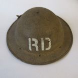 A WW2 metal helmet, painted in drab colours, with white lettering "JWT" and "RD" stencilled at the