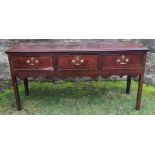 An Antique oak three drawer dresser base, above a shaped apron, raised on square legs, width