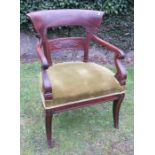 An early 19th century mahogany open arm dining chair, with scroll arms and sabre legs