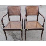 A pair of Regency style cane seated and backed armchairs, raised on slightly outswept faux bamboo