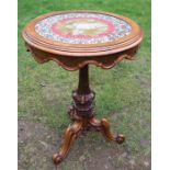A Victorian glass topped centre table, the embroidered top raised on an ornate tripod base, diameter