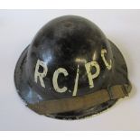 A WW2 metal helmet, painted black with DC/RC in white to one end, impressed 1939 to the rim