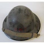 A WW2 metal helmet, painted black with "P.M.T." in red to one end