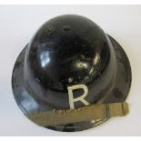 A WW2 metal helmet, painted black with a white "R" to each end