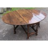 An oval oak gate leg dining table, raised on reeded legs, max length 56ins x 51ins x height 26.5ins