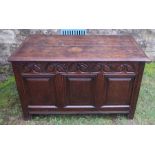 An 18th century oak coffer, having three carved fielded panels to the front, below a lunette