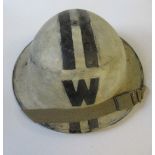 A WW2 metal helmet, painted white with two black stripes and "W" to each end, impressed mark 1939