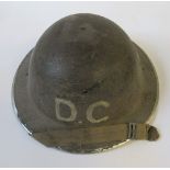 A WW2 metal helmet, painted with "DC" in white to one end